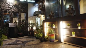 Entrada de hotel com fachada de pedra, plantas em vasos e uma placa com a inscrição 'SAINT PALUS'.