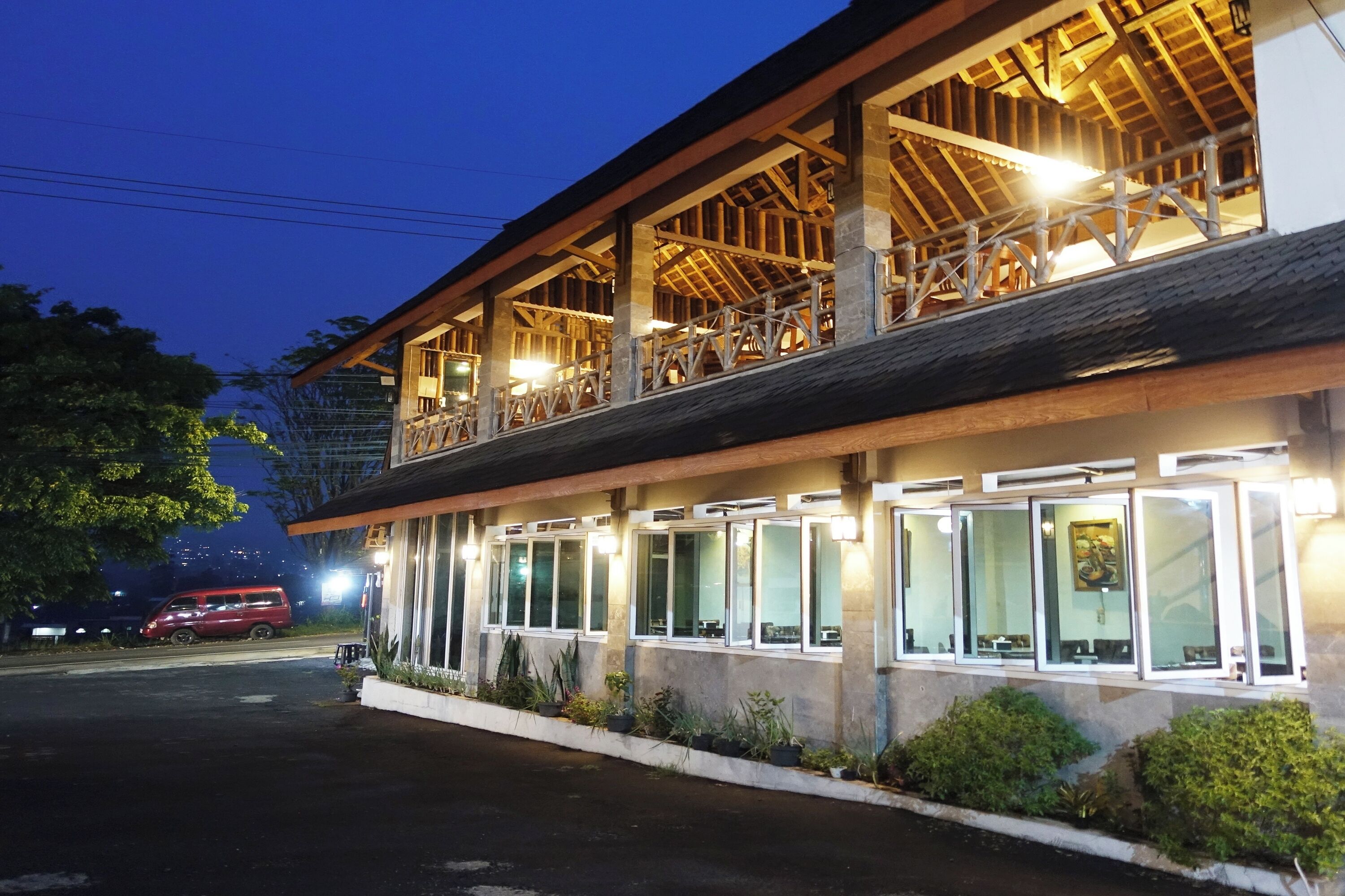 A two-story building with a wooden balcony and large windows.