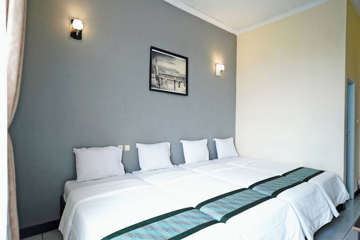 A hotel room with a large bed, two wall-mounted lights, and a framed picture on the wall.
