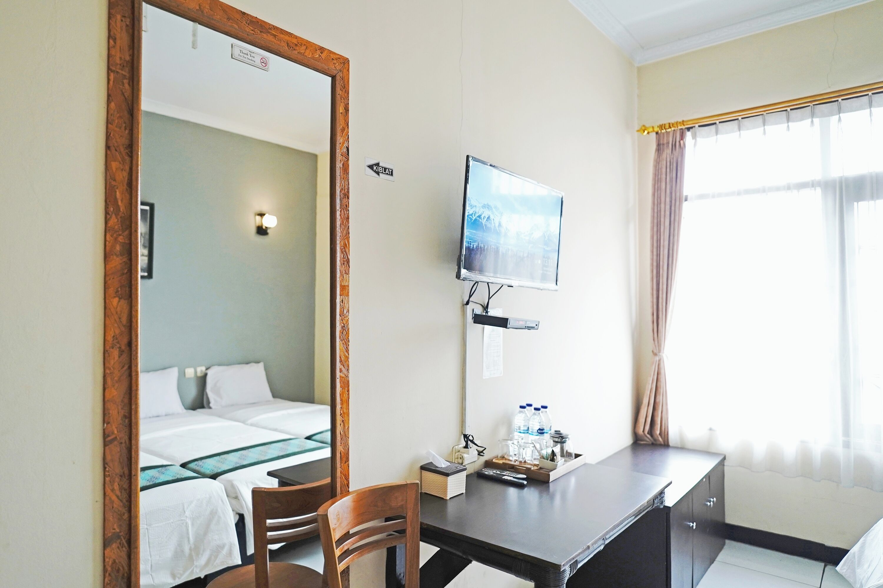 A hotel room with a bed, a desk, a chair, a television, and a window with curtains.