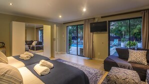 A hotel room with a bed, a sofa, a TV, and a view of an outdoor swimming pool. - Atlantic Bay Lodge (Cape Town)