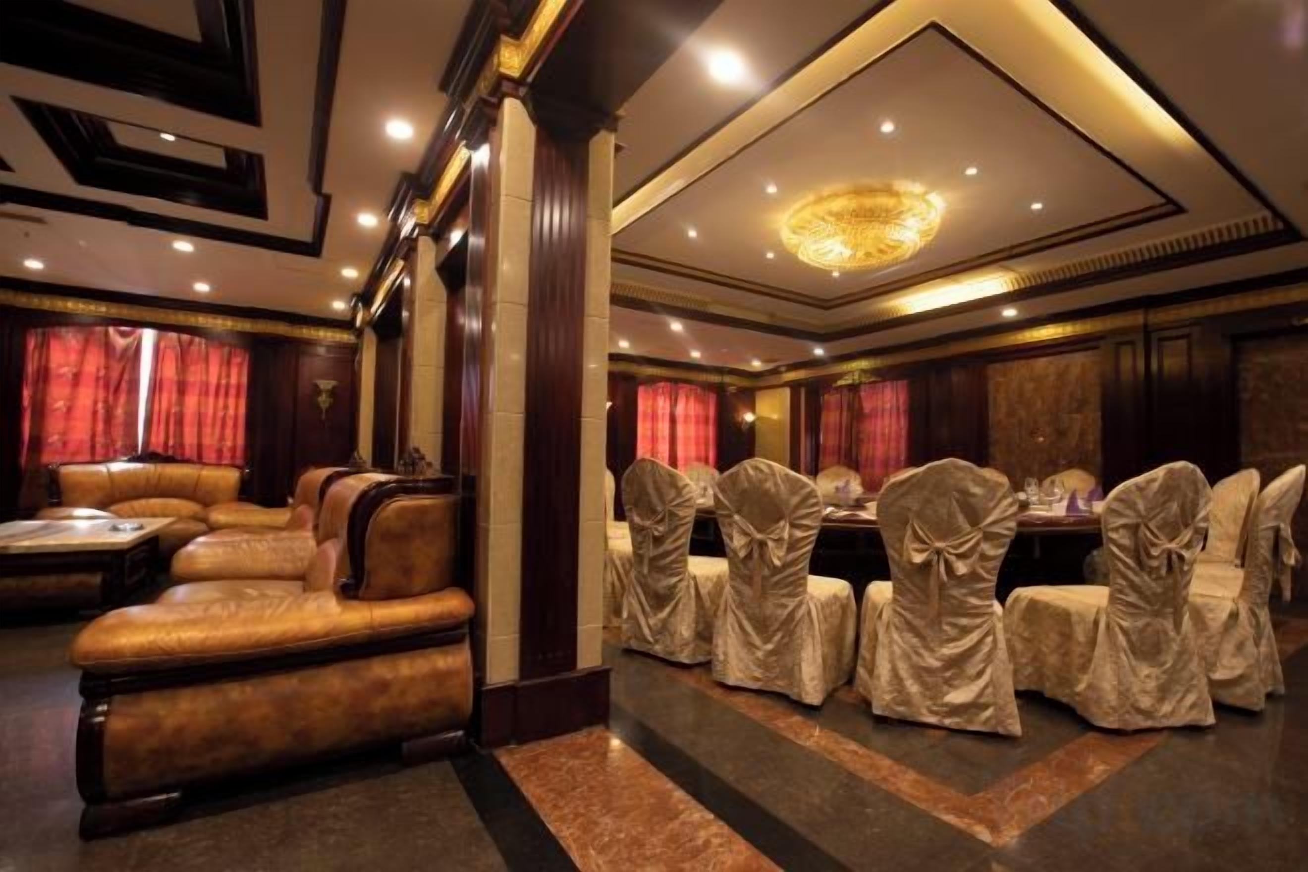 Ein Hotelzimmer mit einer Sitzecke, einem Esstisch und Stühlen, die mit Tischdecken bedeckt sind.