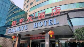 Een hotelingang met borden in een vreemde taal, een overdekt portaal en een moderne gevel.