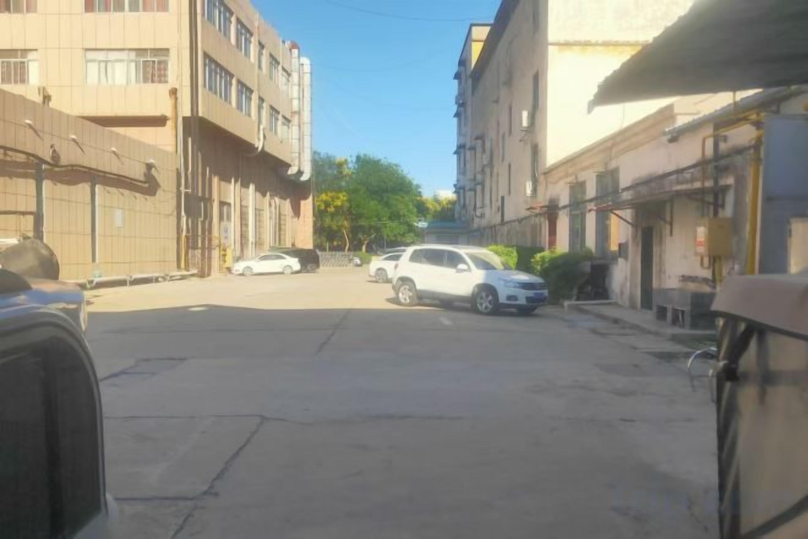 A street with buildings on both sides, a white car parked on the side, and a clear sky.