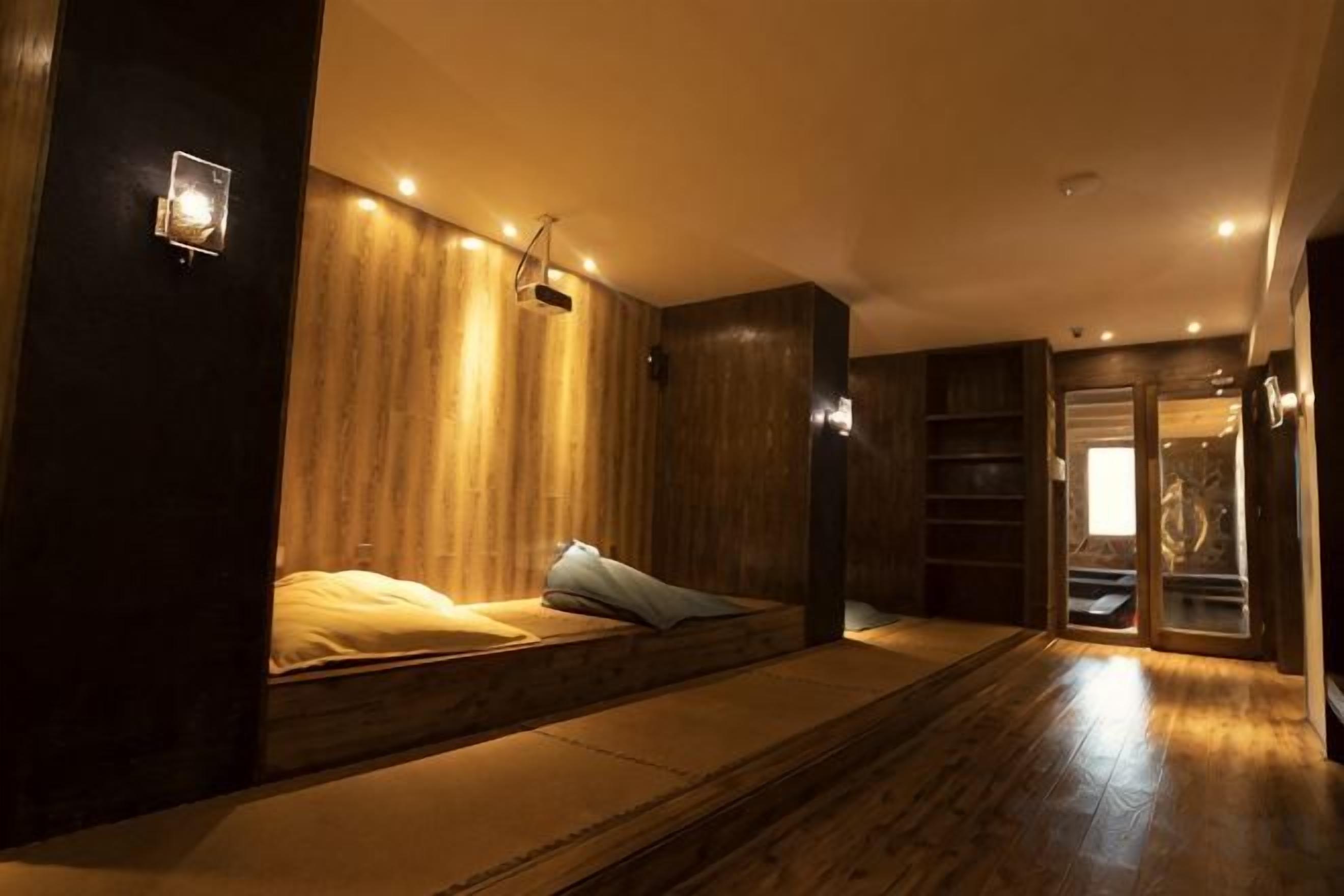 A room with a bed, wooden paneling, and a built-in shelf.