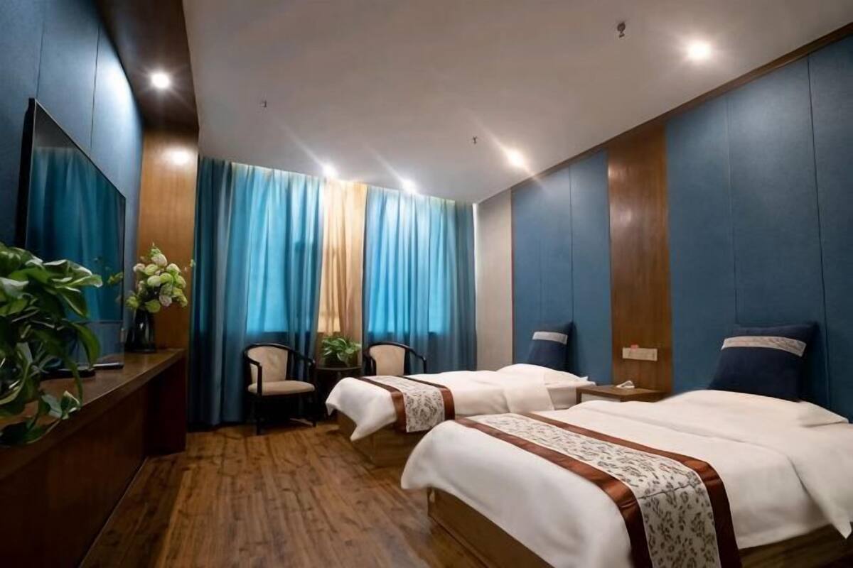 A hotel room with two beds, a desk, chairs, and a large mirror.