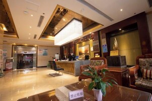 Vestíbulo de hotel con mostrador de recepción, zona de estar y una planta grande.