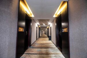 Un pasillo largo y estrecho en un hotel, con puertas a ambos lados, iluminado por luces del techo.