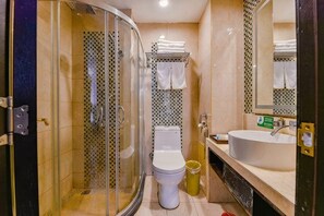 A bathroom with a glass-enclosed shower, a toilet, and a sink.