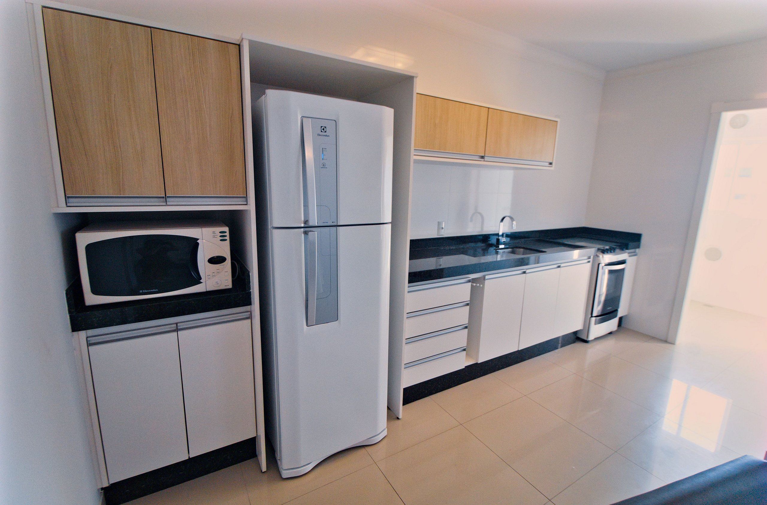 A modern kitchen with white cabinets, a built-in microwave, a refrigerator, a stove, and a sink.