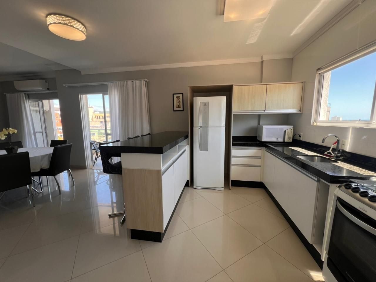 A modern kitchen with a central island, built-in appliances, and a dining area with chairs.