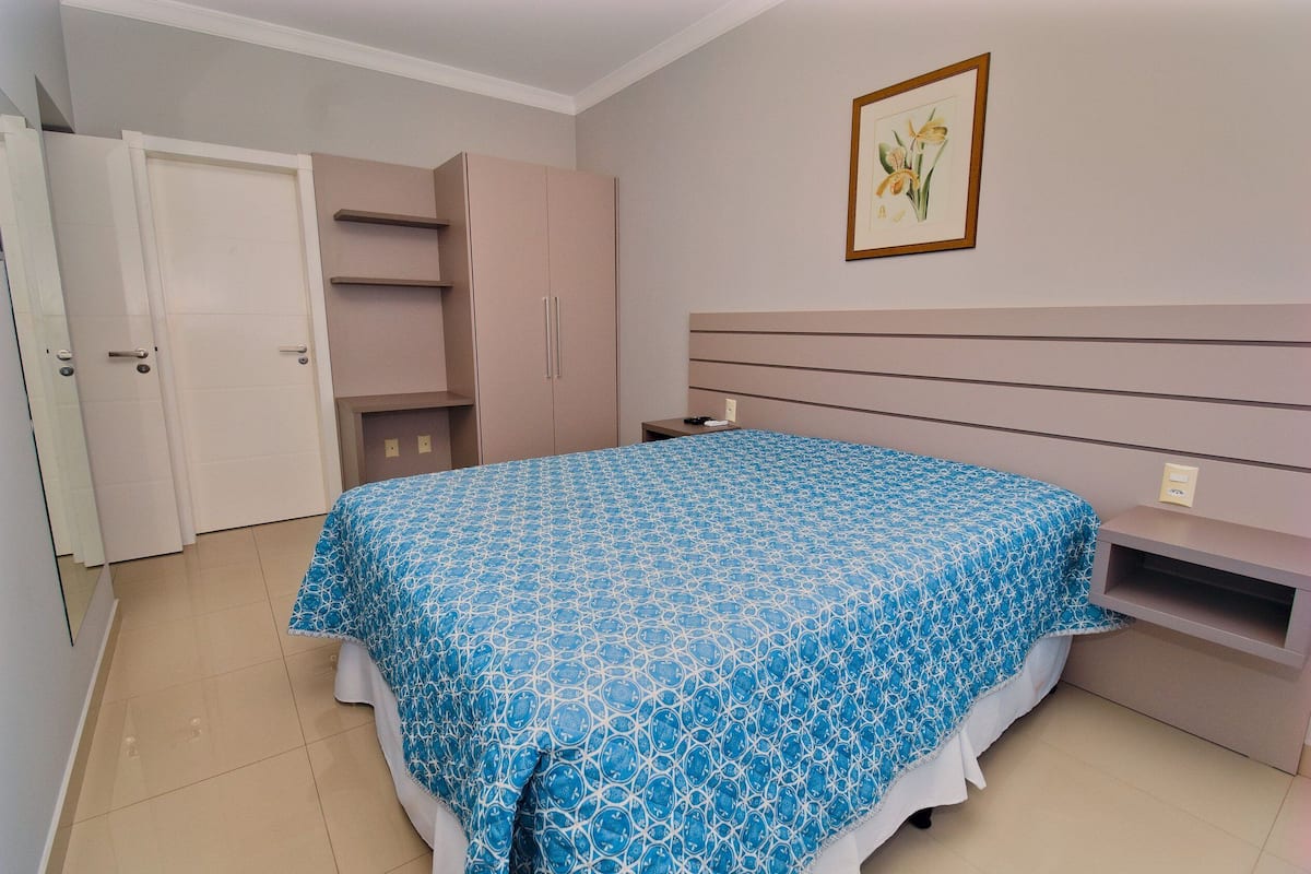 Une chambre à coucher avec un lit, une armoire, une table de chevet et un tableau encadré au mur.
