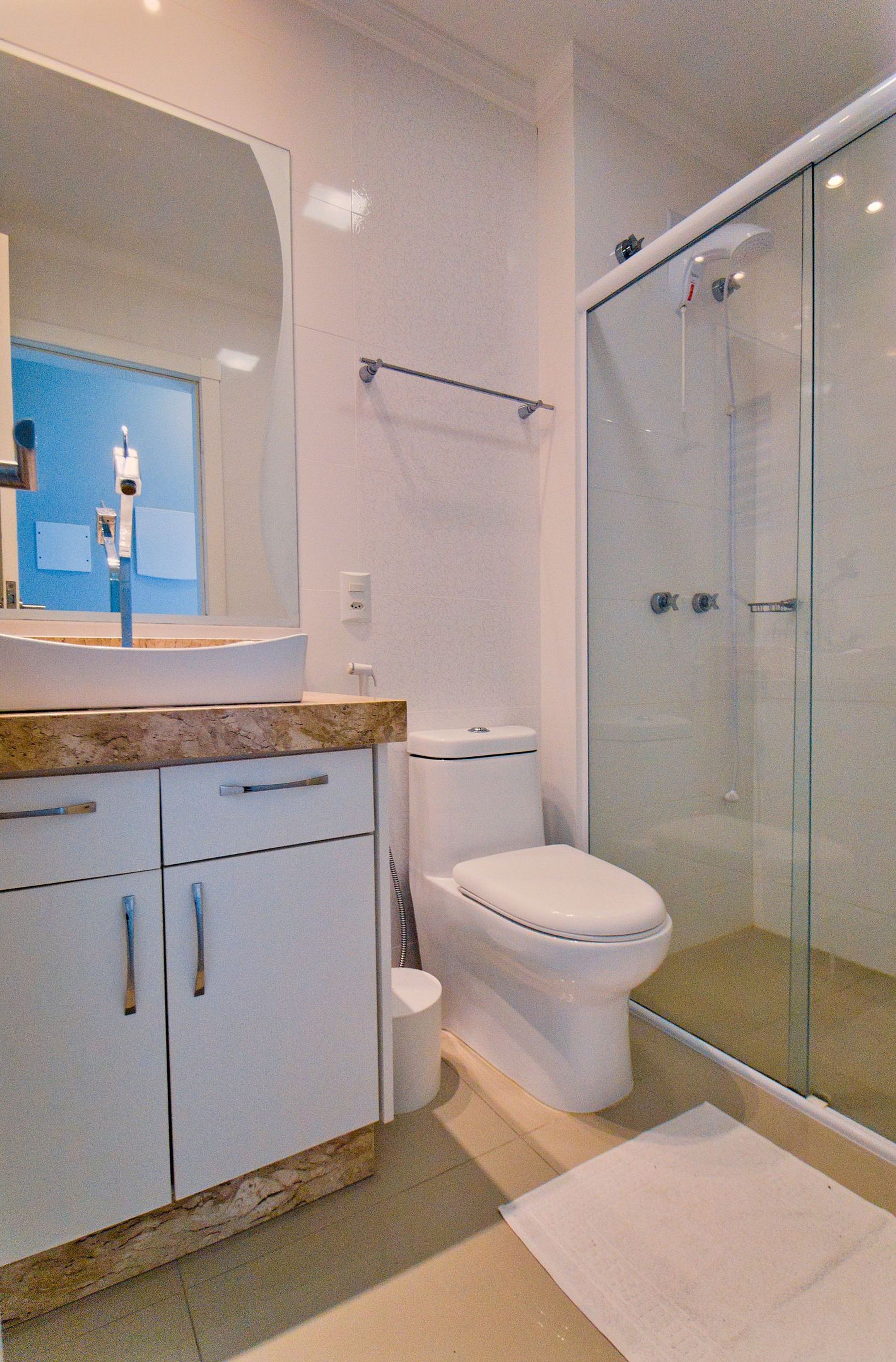 A modern bathroom with a glass-enclosed shower, a white toilet, and a marble countertop with a sink.