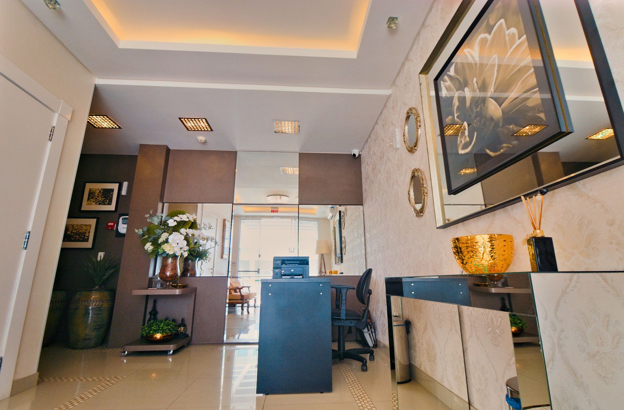 A modern reception area with a reception desk, seating, and a large mirror.