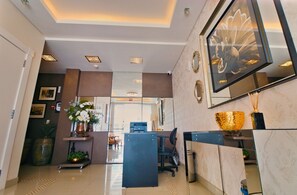 A modern reception area with a reception desk, seating, and a large mirror.