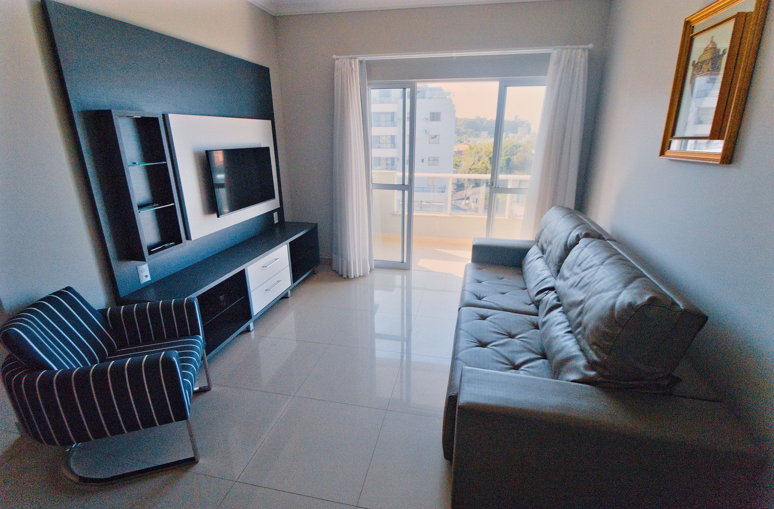 A modern living room with a flat-screen TV, a sofa, and a striped armchair.