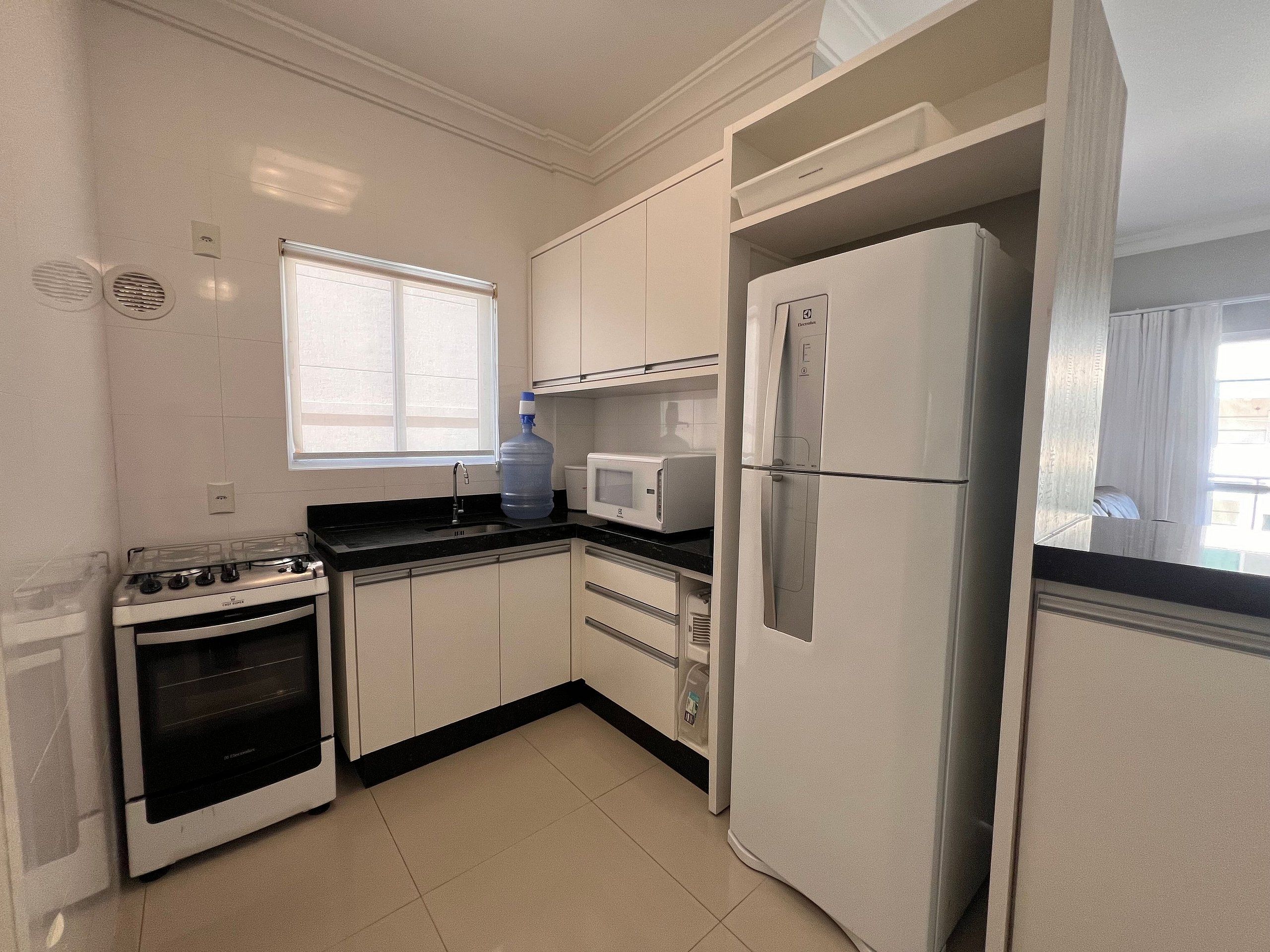A kitchen with white cabinets, a stove, a refrigerator, and a microwave.