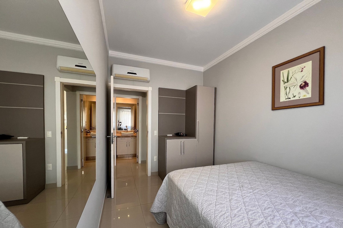 Une chambre à coucher avec un lit, une armoire et une salle de bain visible à travers une porte ouverte.
