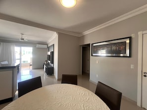 Una sala moderna con comedor, cocina y balcón.