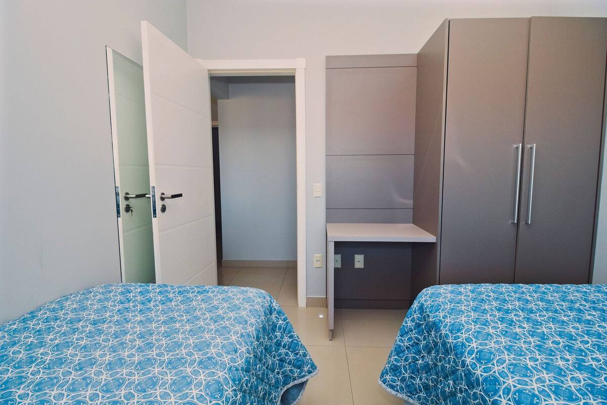 Une chambre avec deux lits, une armoire et un bureau.