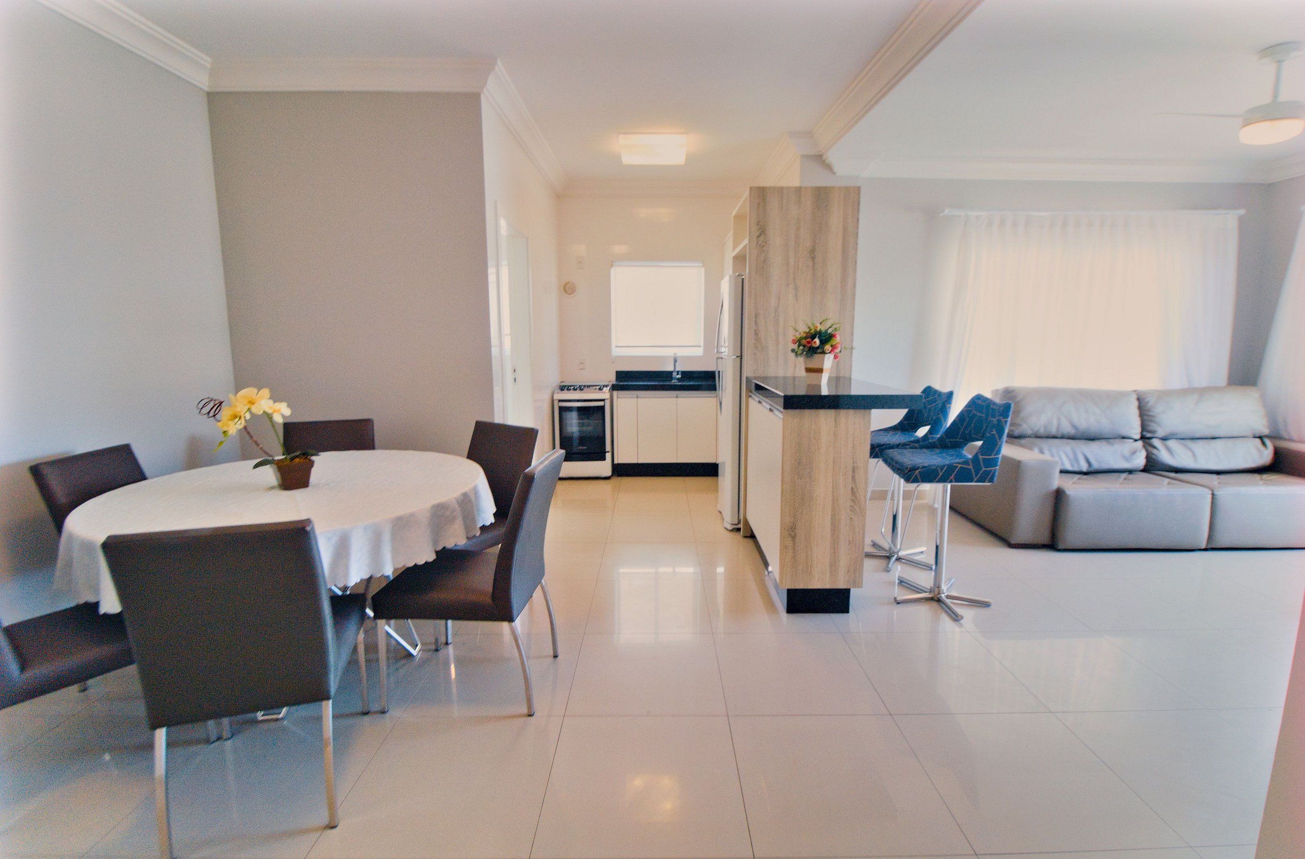 A modern living room with a dining area, a kitchen, and a sofa.