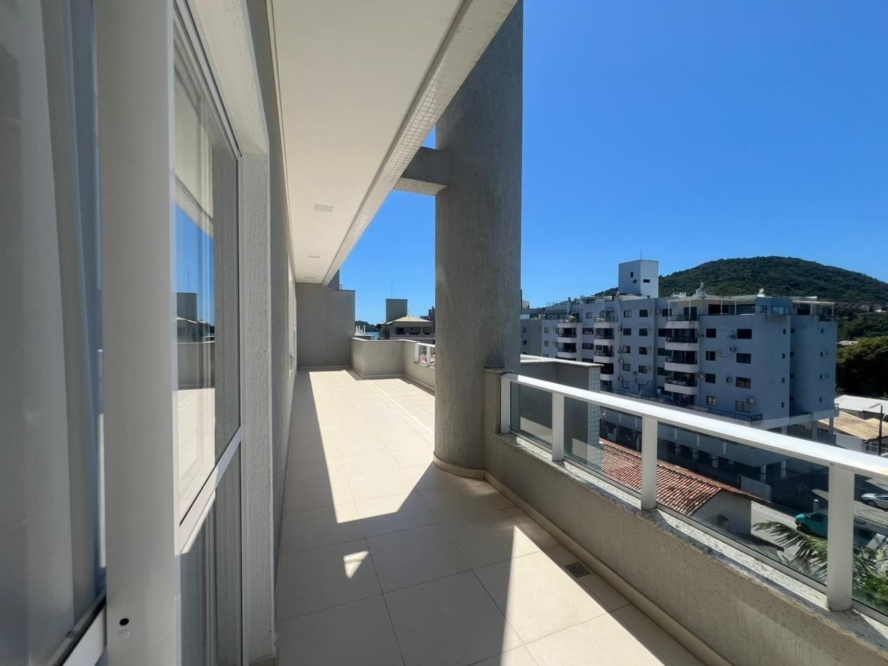 A balcony with a clear view of surrounding buildings and a hill.
