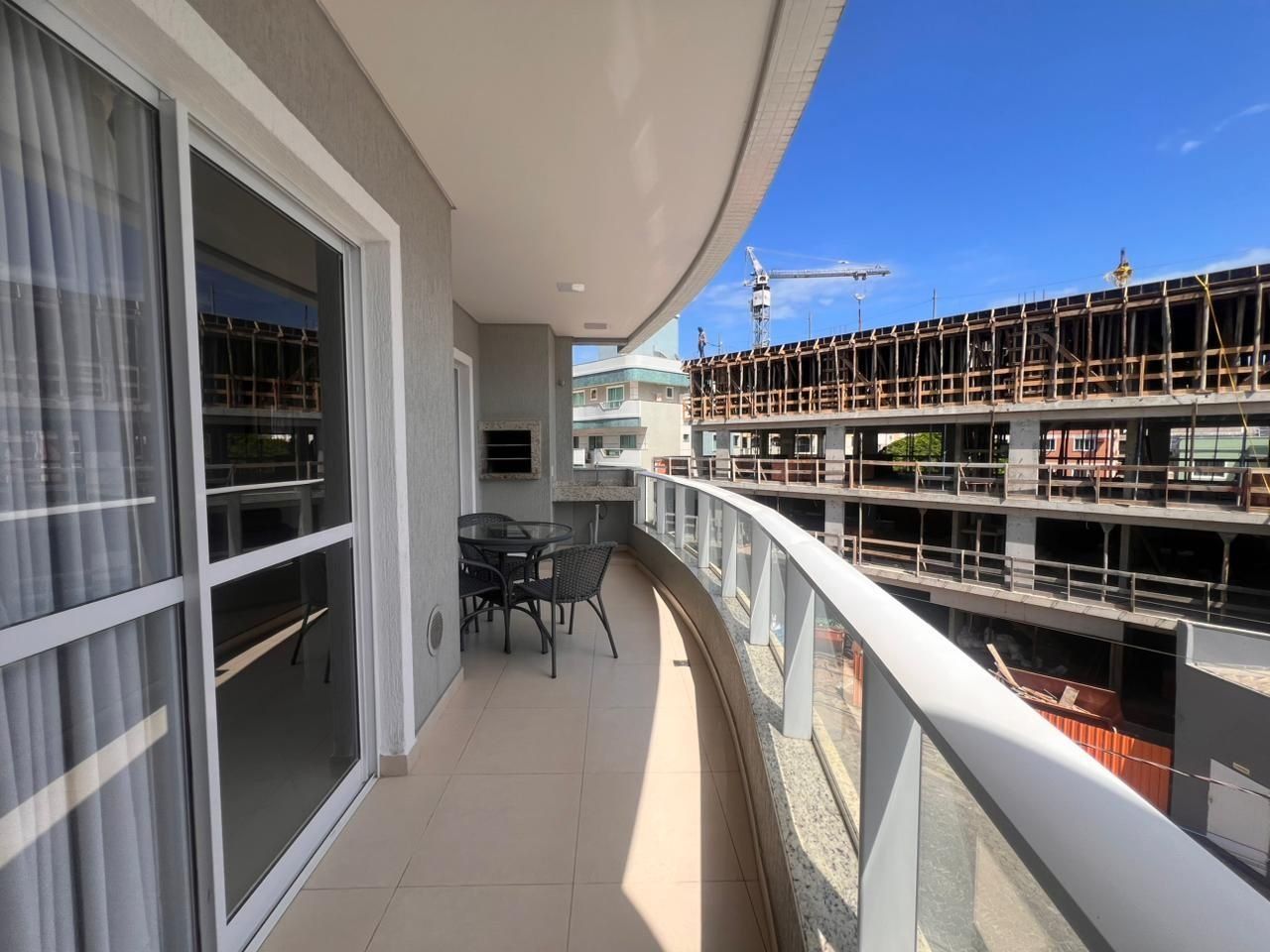 A balcony with a glass door, a table with chairs, and a view of a construction site.