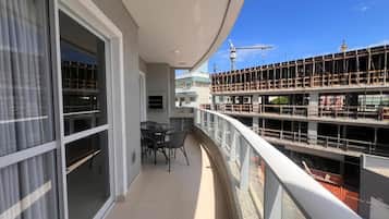 A balcony with a glass door, a table with chairs, and a view of a construction site.