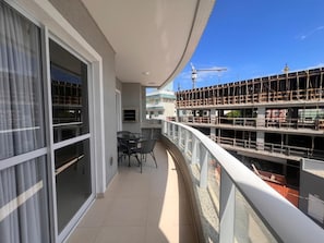 A balcony with a glass door, a table with chairs, and a view of a construction site.