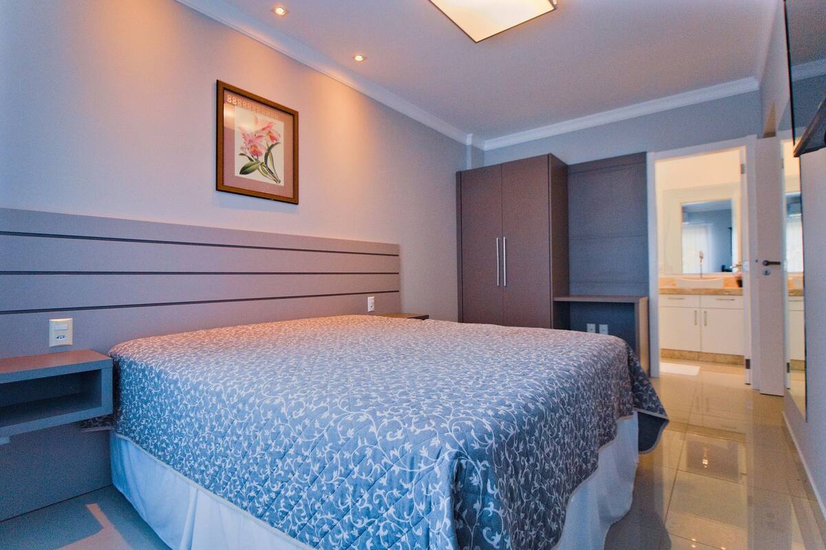 Une chambre à coucher avec un lit, une table de chevet, une armoire et un tableau encadré au mur.