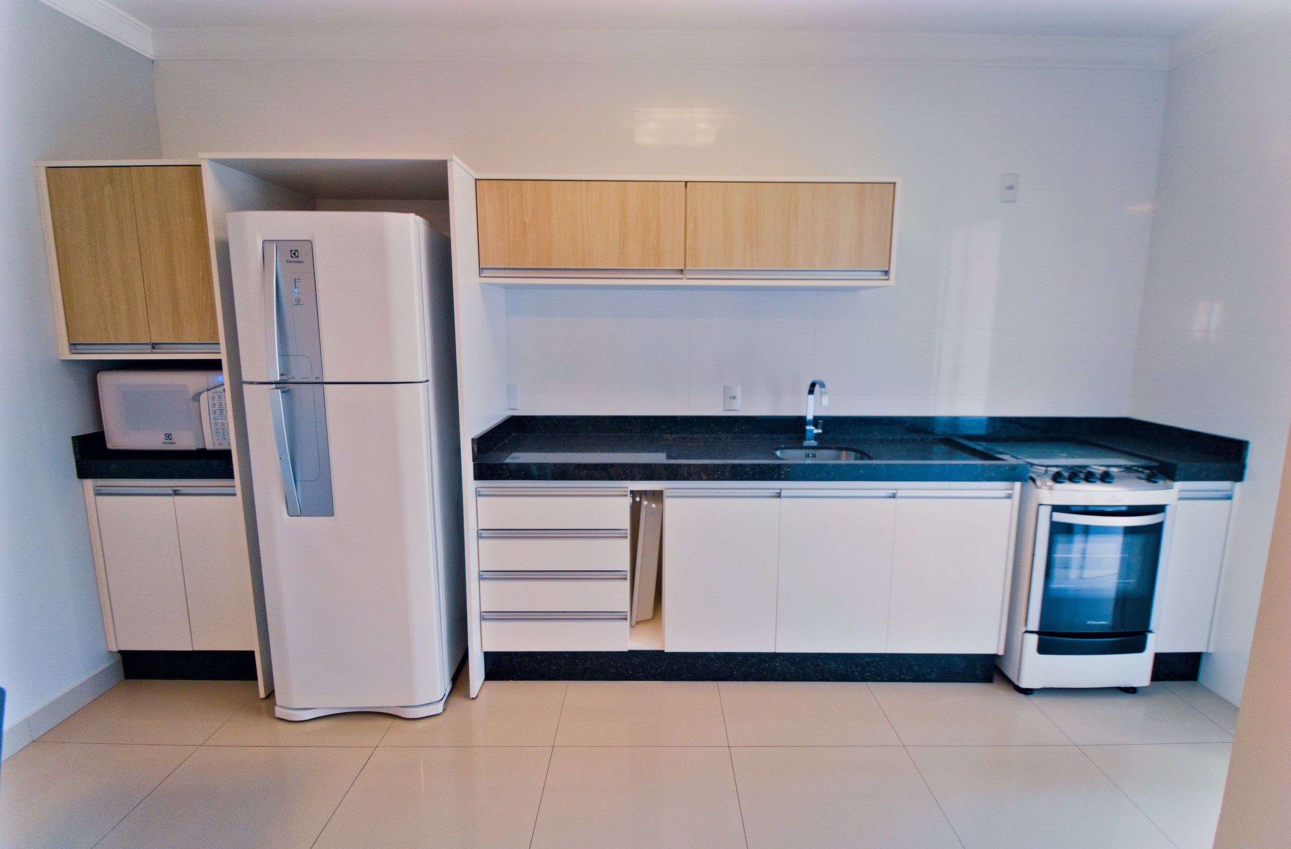 A modern kitchen with white cabinets, a built-in oven, a refrigerator, and a microwave.