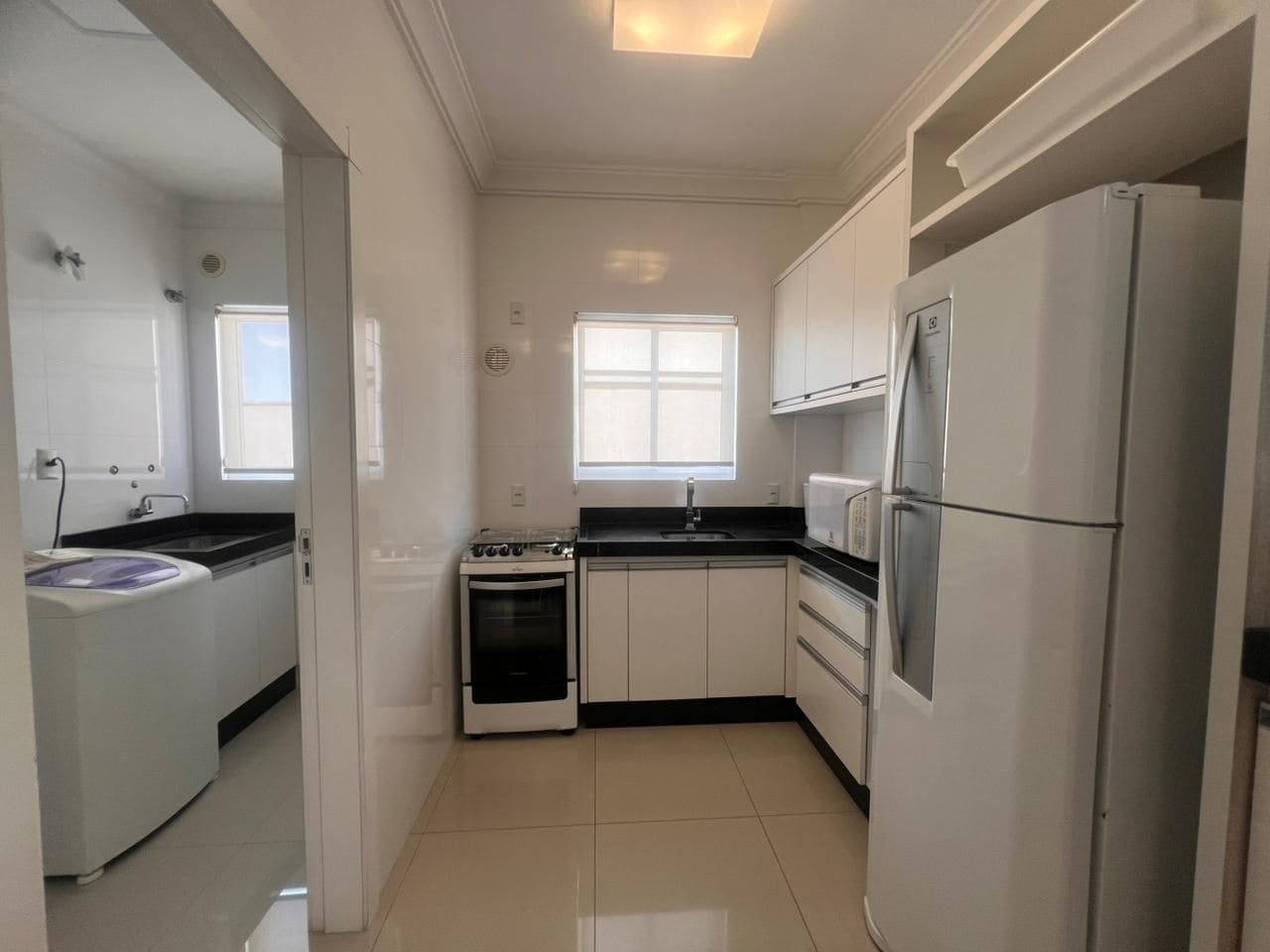 A compact kitchen with white cabinets, a stove, a microwave, and a refrigerator.