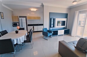 A modern living space with a dining area, kitchen, and seating area. -  Residencial Baía dos Golfinhos (Bombinhas)