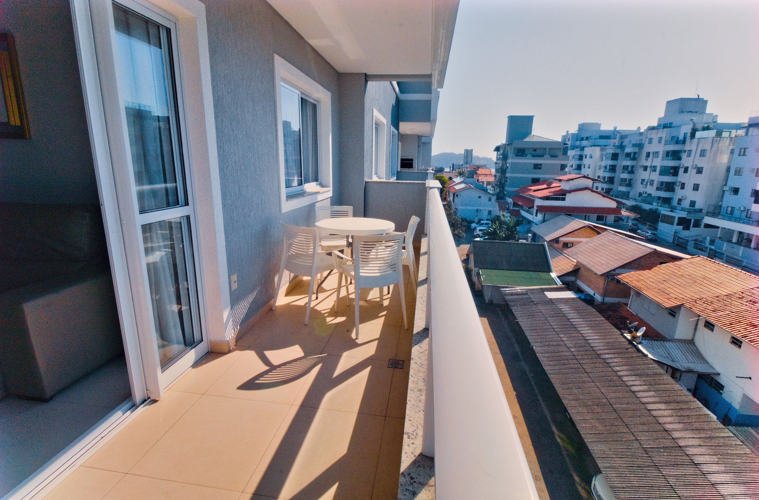 A balcony with a table and chairs, overlooking a residential area with buildings.