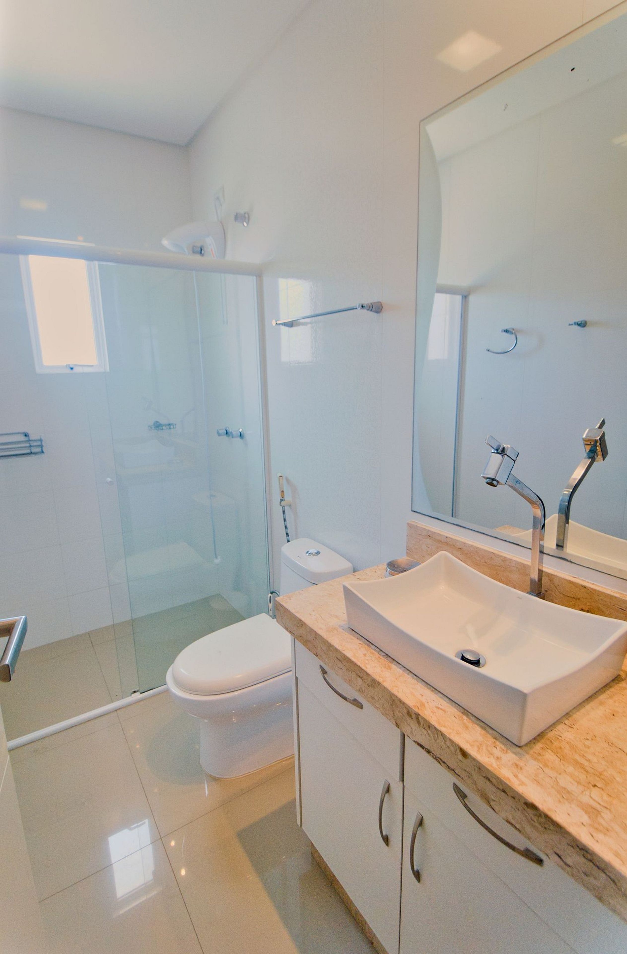 A modern bathroom with a glass shower enclosure, a white toilet, and a sink with a marble countertop.
