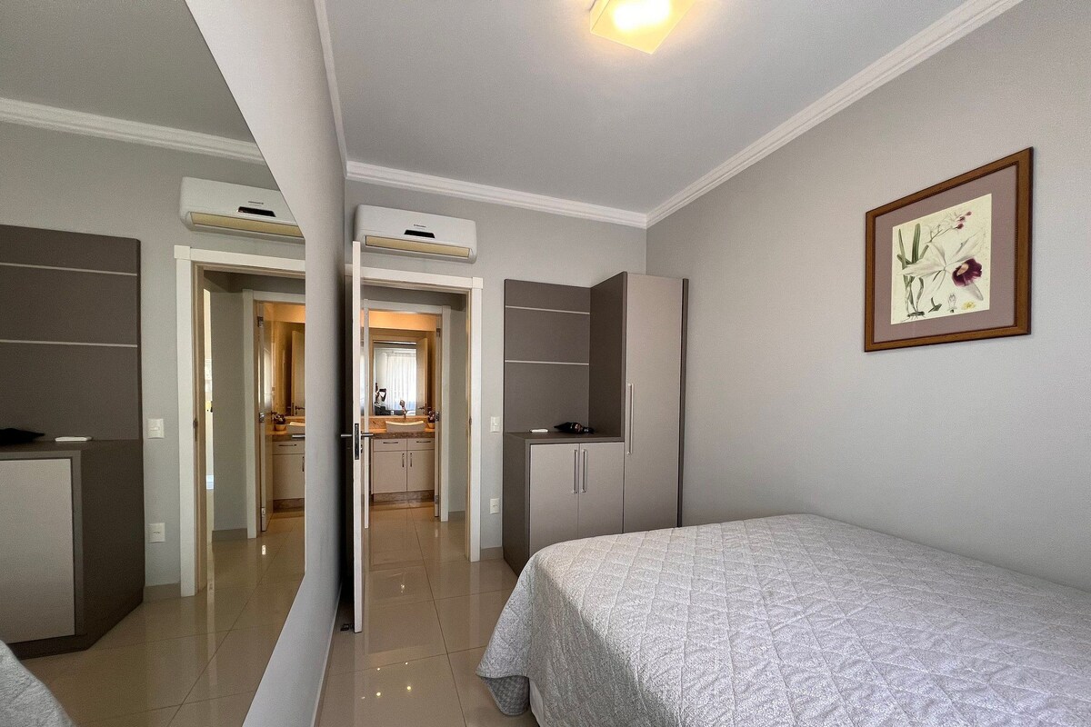 A bedroom with a bed, a wardrobe, and a bathroom visible through an open door.
