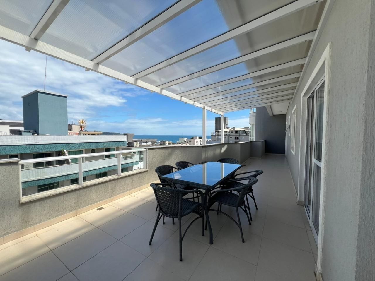 A covered outdoor patio with a table and chairs, overlooking a cityscape.