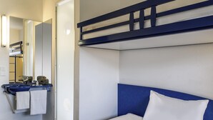 A hotel room with a bunk bed, a bedside table with a tablet and headphones, a sink with a towel, and a mirror. - Ibis Budget Libourne (Libourne)