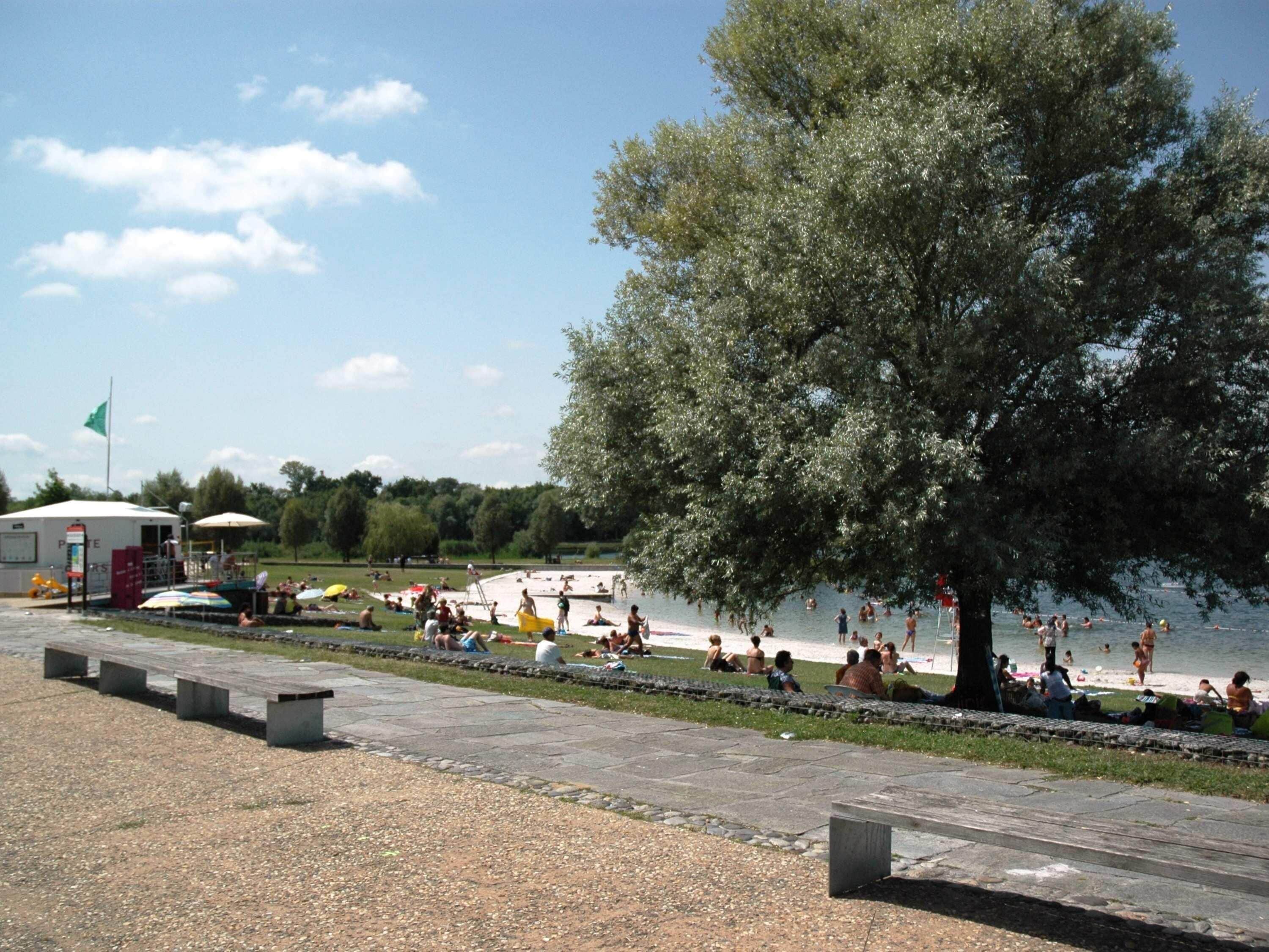 Ein Park am Seeufer mit Badestrand, Picknicktischen und einem überdachten Pavillon.