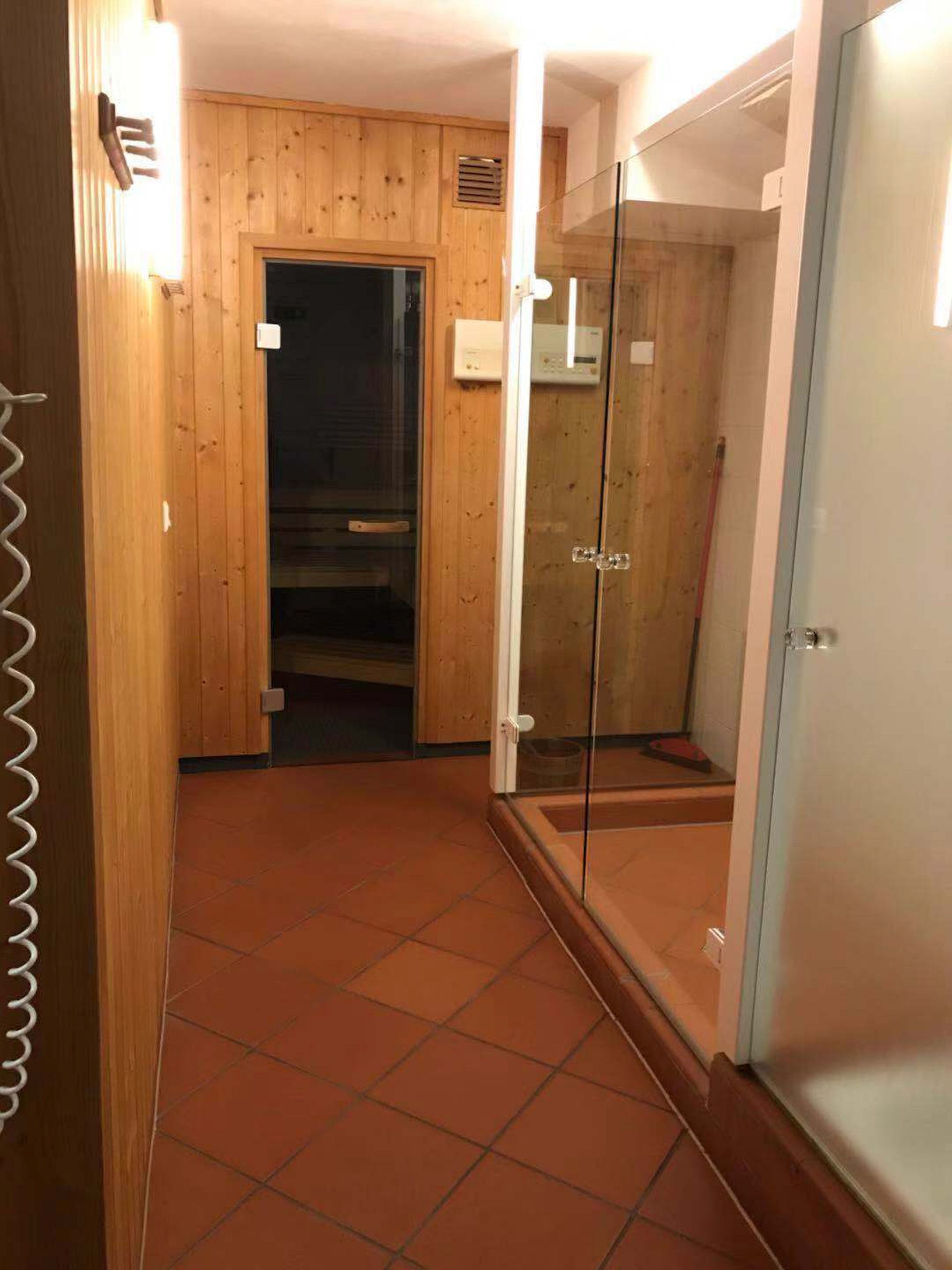 A room with wooden panel walls, a glass shower enclosure, and a tiled floor.