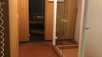 A room with wooden panel walls, a glass shower enclosure, and a tiled floor.