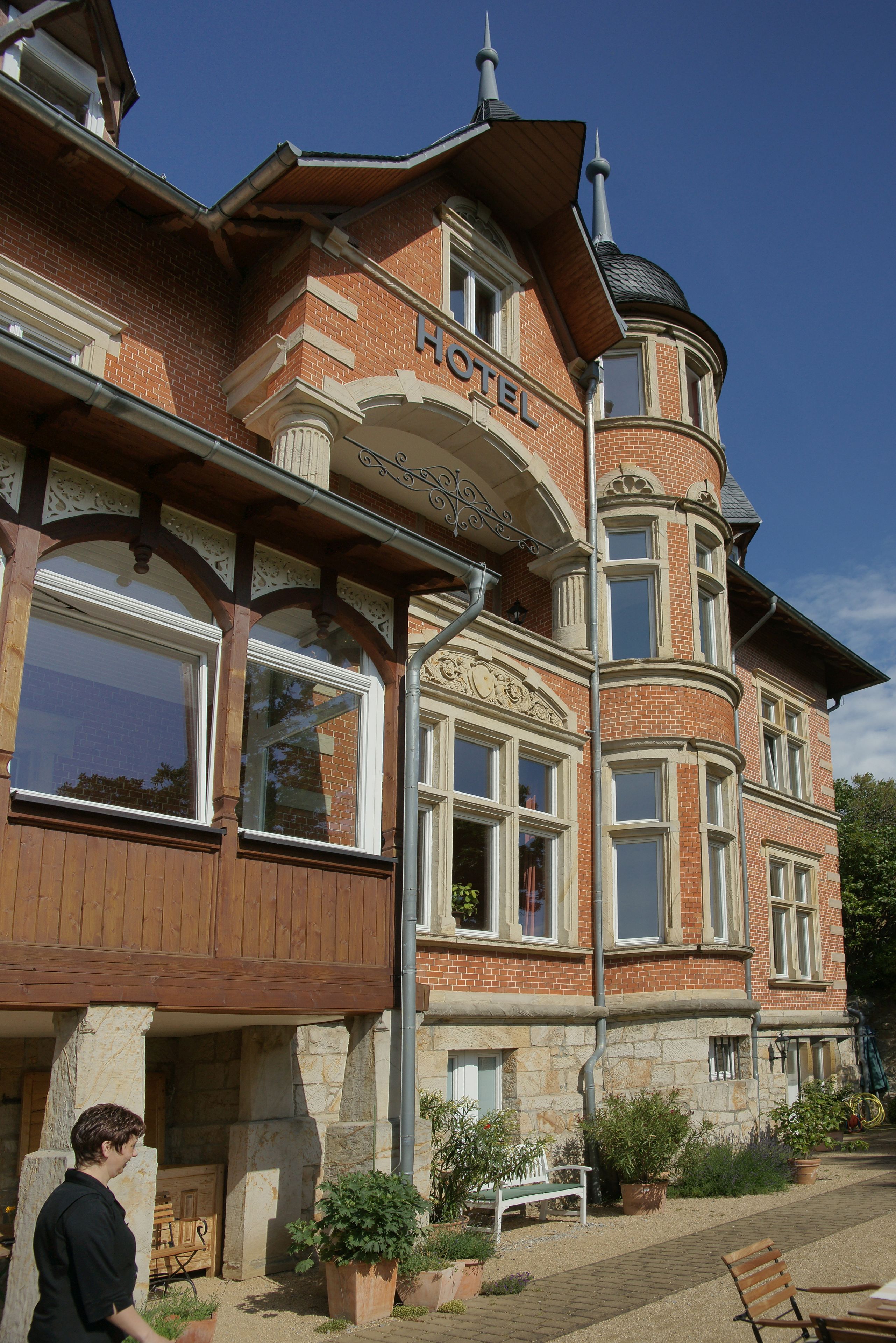 Un hôtel à la façade en briques, doté de grandes fenêtres et d’un balcon.