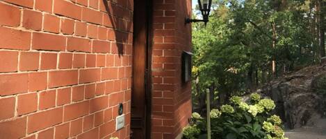 Un edificio de ladrillo con un porche cubierto, iluminación exterior y plantas en macetas.
