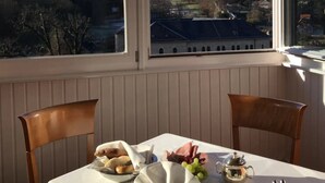 A dining area with a table set for two, overlooking a hill with a castle-like structure. - Hotel Villa Viktoria Luise (Blankenburg)