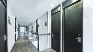 A modern hotel corridor with glass railings, dark doors, and numbered room signs. - Hotel Cartagena DC (Cartagena)