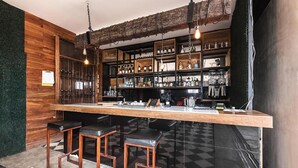A bar area with a wooden counter, black stools, and shelves stocked with bottles and glasses. - Hotel Cartagena DC (Cartagena)