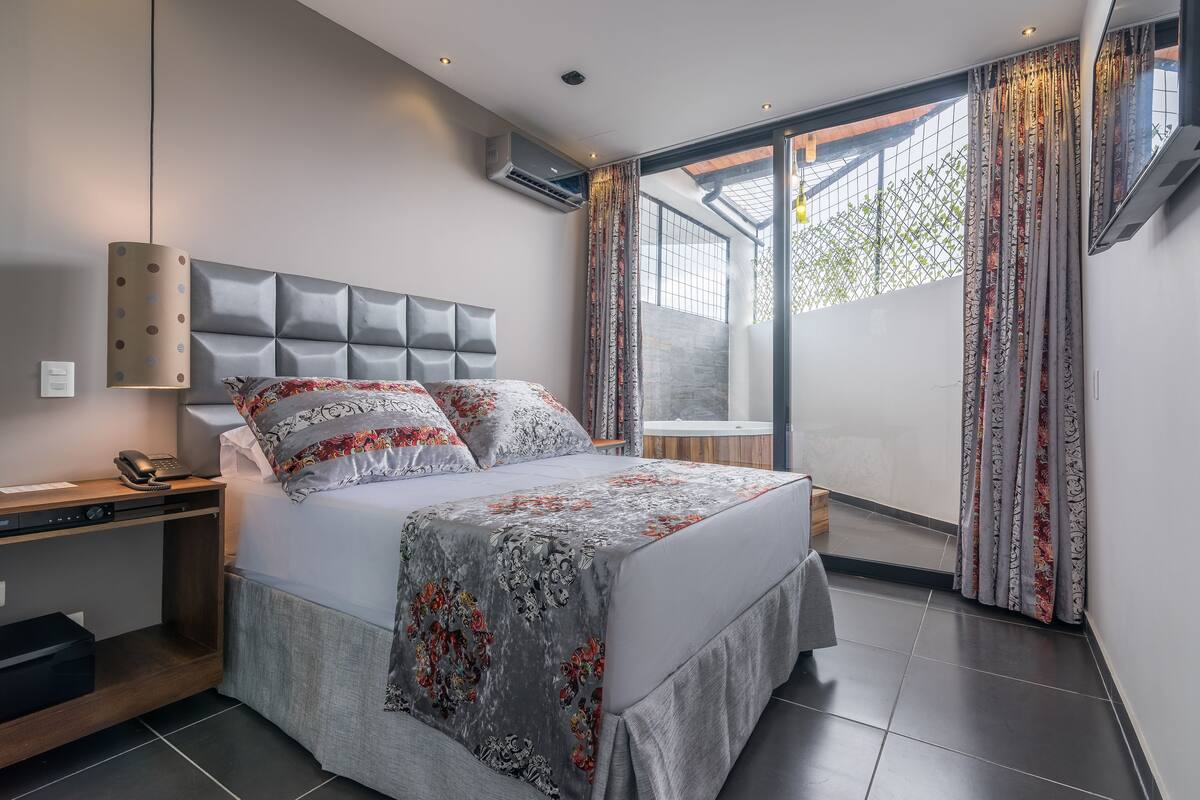 A modern bedroom with a bed, bedside table, and an air conditioning unit.