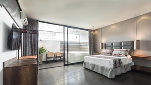 A modern bedroom with a large bed, a sliding glass door to a balcony, and a flat-screen TV mounted on the wall. - Hotel Cartagena DC (Cartagena)
