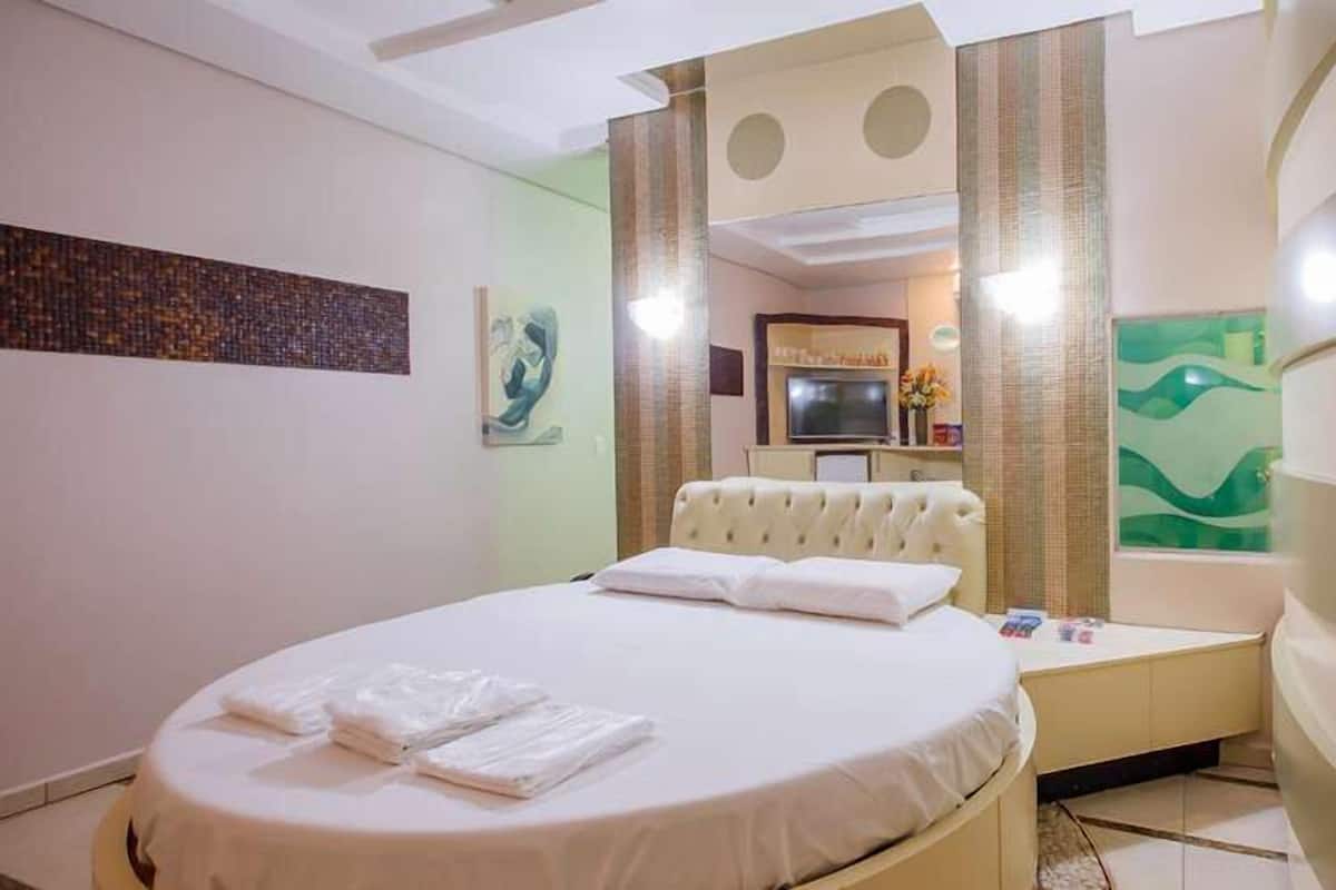 A hotel room with a bed, a vanity with a mirror, and a bathroom with a bathtub.
