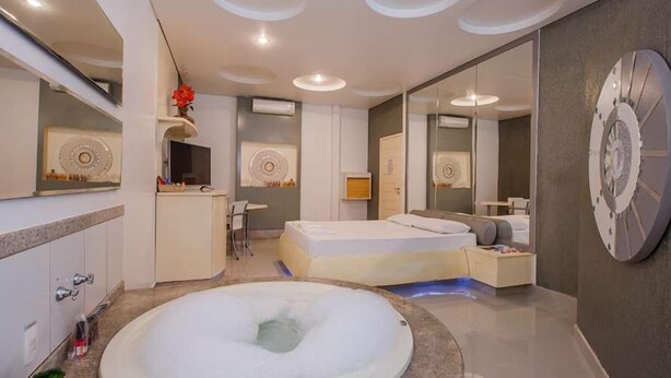 A modern bathroom with a large bathtub, a vanity with a mirror, and a separate bedroom area.